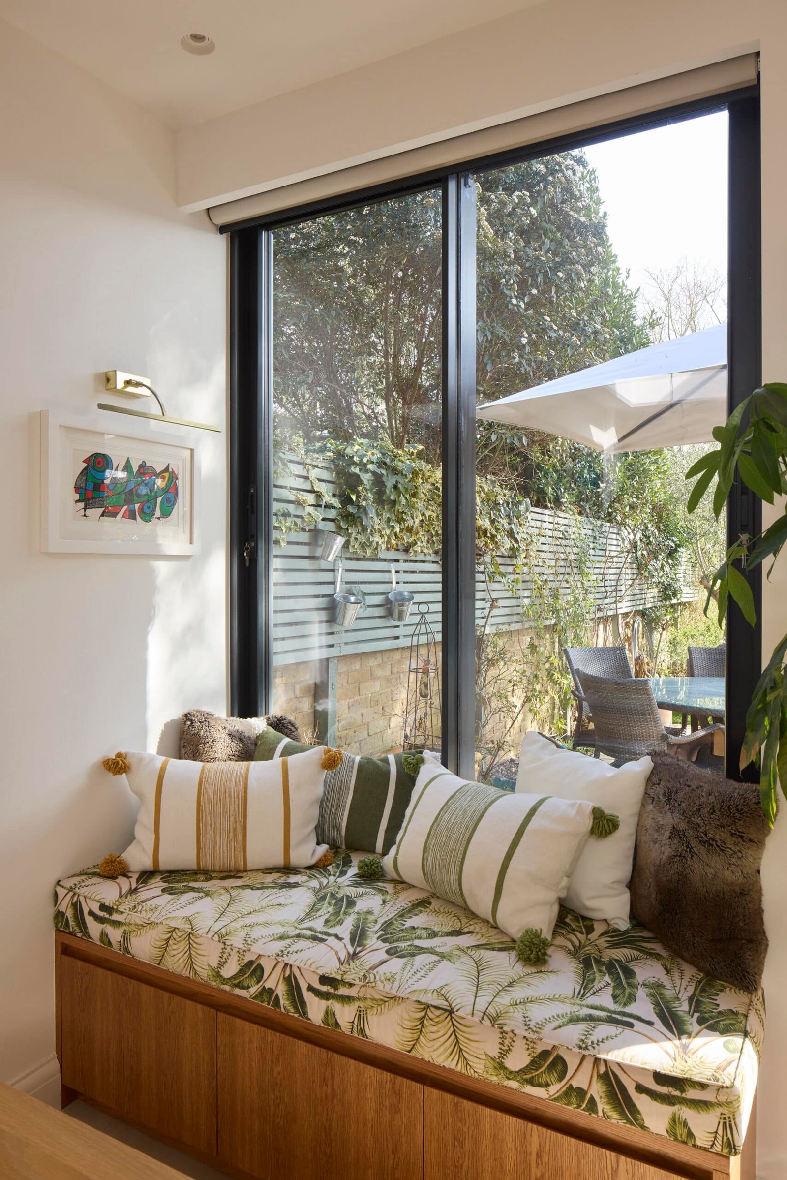 Modern sitting room with floor-to-ceiling sliding glass doors overlooking landscaped garden